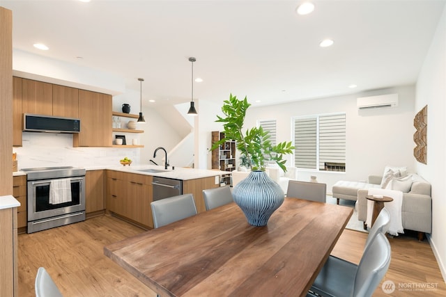 kitchen featuring appliances with stainless steel finishes, a sink, open shelves, light countertops, and light wood-style floors