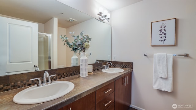 bathroom with a stall shower, double vanity, and tasteful backsplash
