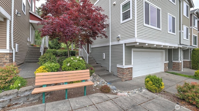 view of home's exterior with an attached garage, stairway, driveway, and stone siding