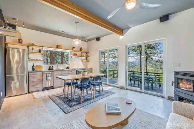 981 Nighthawk Ridge Ln, Leavenworth, WA 98826 - dining space with finished concrete flooring, beamed ceiling, rail lighting, a ceiling fan, and a wood stove