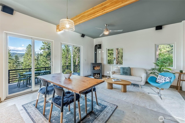 981 Nighthawk Ridge Ln, Leavenworth, WA 98826 - dining area featuring a wood stove, beamed ceiling, ceiling fan, and concrete flooring