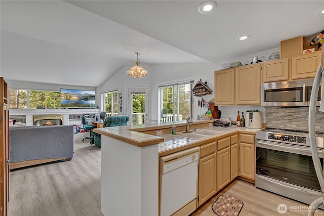 5400 Harbour Pointe Blvd Unit F202, Mukilteo, WA 98275 - kitchen featuring stainless steel appliances, a sink, a peninsula, lofted ceiling, and light brown cabinetry