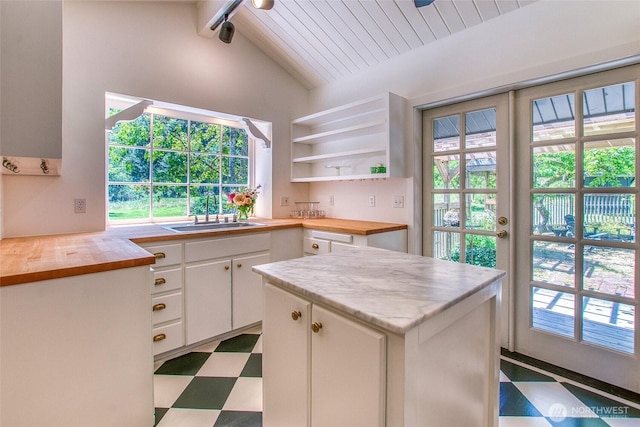 1472 White Beach Rd, Orcas Island, WA 98280 - kitchen with butcher block countertops, tile patterned floors, white cabinets, and healthy amount of natural light