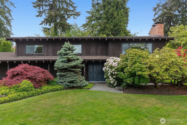 mid-century modern home with a front lawn, a chimney, and board and batten siding