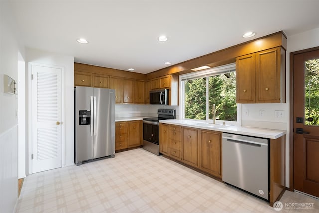 kitchen featuring appliances with stainless steel finishes, a sink, light countertops, plenty of natural light, and recessed lighting