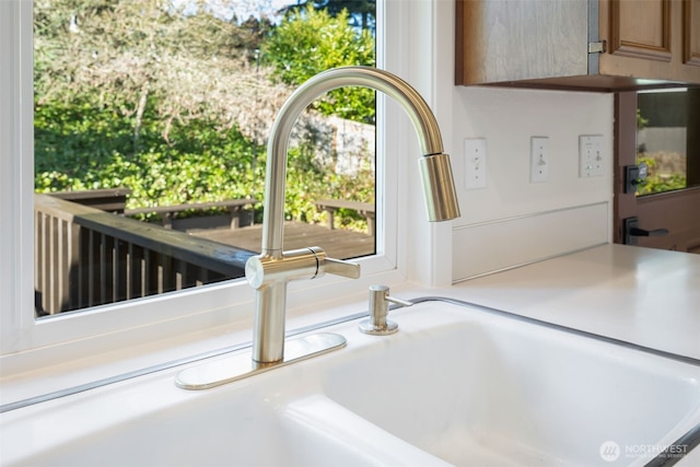 kitchen view of a sink, light countertops, and brown cabinetry