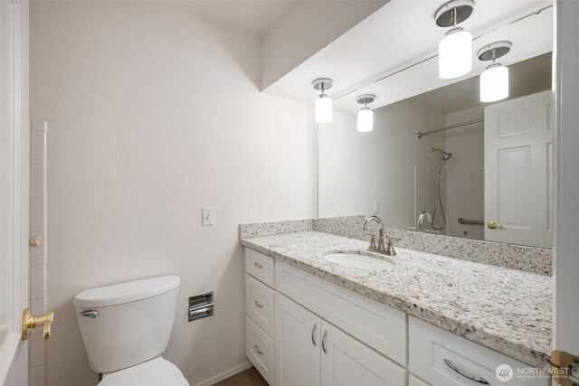 bathroom featuring toilet, a shower, and vanity