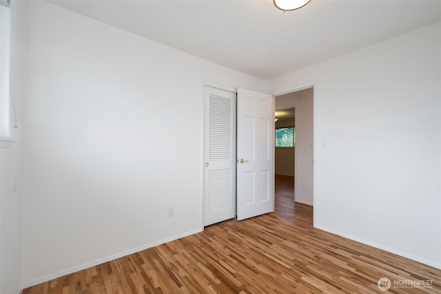unfurnished bedroom with light wood-type flooring, a closet, and baseboards