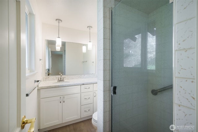full bath featuring a stall shower, vanity, toilet, and wood finished floors