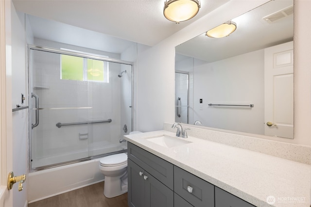 full bathroom featuring wood finished floors, vanity, toilet, and bath / shower combo with glass door