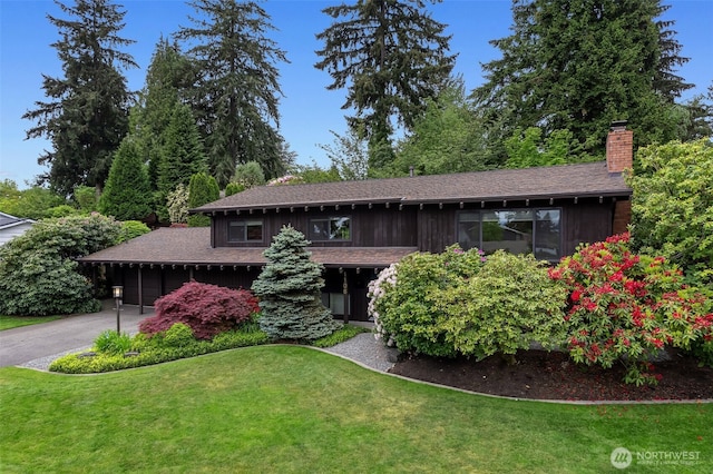 view of front of property with a chimney, a front lawn, asphalt driveway, and an attached garage