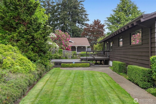 view of green lawn featuring a wooden deck