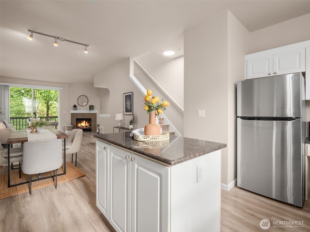 3116 164th St SW Unit 1804, Lynnwood, WA 98087 - kitchen featuring freestanding refrigerator, a tile fireplace, light wood-type flooring, white cabinetry, and a kitchen island