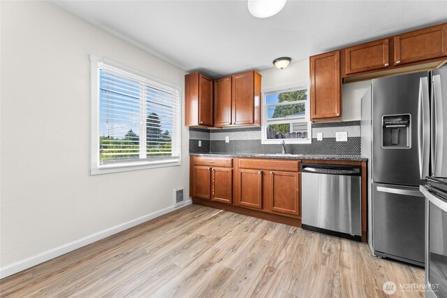 807 S Howard St, Tacoma, WA 98465 - kitchen with stainless steel appliances, light wood-style flooring, decorative backsplash, and dark countertops