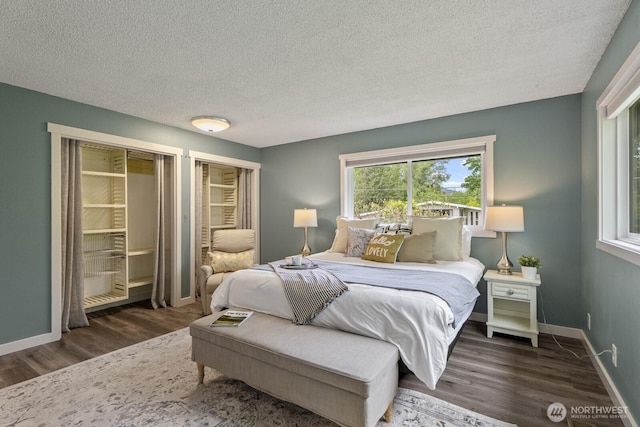 436 SE Maple Dr, North Bend, WA 98045 - bedroom featuring wood finished floors, a textured ceiling, baseboards, and multiple closets