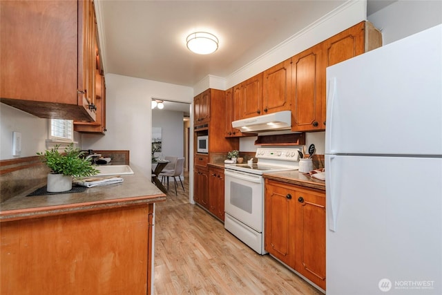 kitchen with white appliances, under cabinet range hood, a sink, light wood-type flooring, and brown cabinets