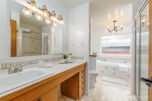 full bath featuring a chandelier, a stall shower, vanity, a garden tub, and toilet