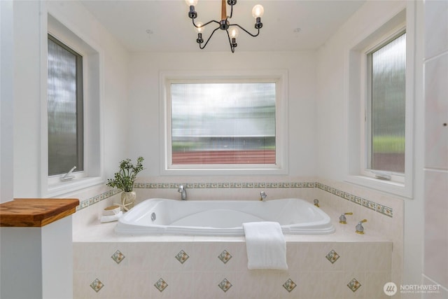 full bath featuring plenty of natural light, a bath, and a chandelier