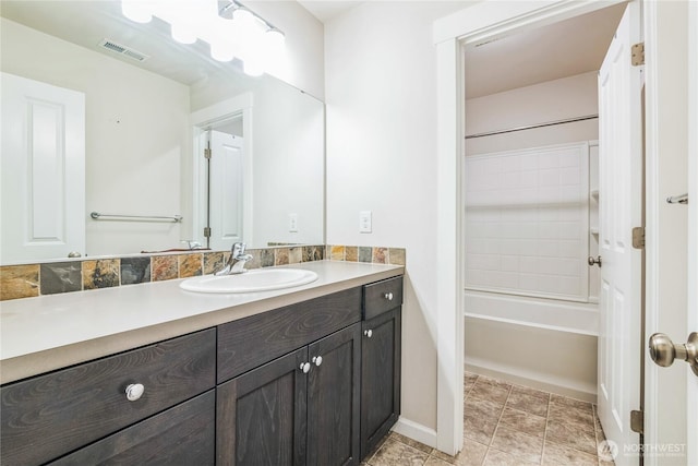bathroom featuring vanity, baseboards, and tub / shower combination