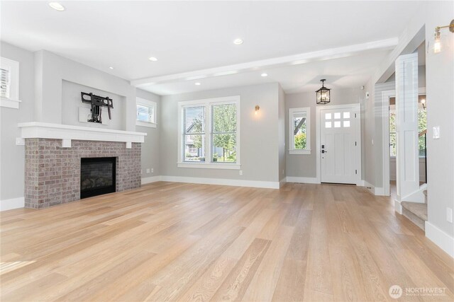 unfurnished living room with light wood finished floors, baseboards, recessed lighting, a fireplace, and a chandelier