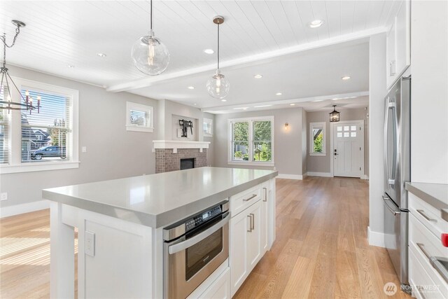 kitchen featuring light wood finished floors, stainless steel appliances, open floor plan, baseboards, and recessed lighting