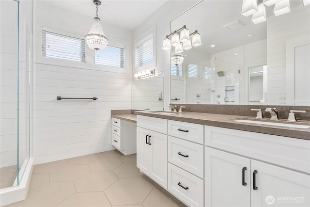 full bathroom with a shower stall, tile walls, a chandelier, double vanity, and tile patterned flooring