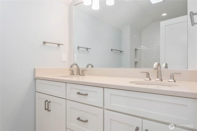 bathroom with double vanity, vaulted ceiling, a shower, and recessed lighting