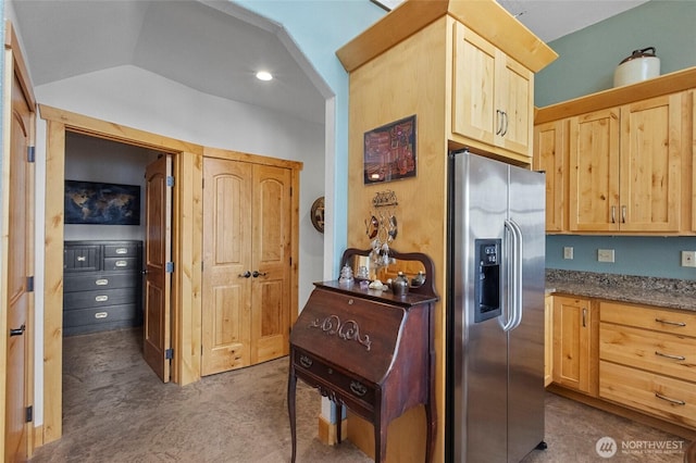 kitchen with stainless steel fridge with ice dispenser, light brown cabinetry, vaulted ceiling, and carpet floors