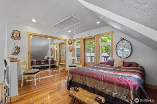 bedroom with attic access, vaulted ceiling, light wood-style floors, recessed lighting, and access to outside