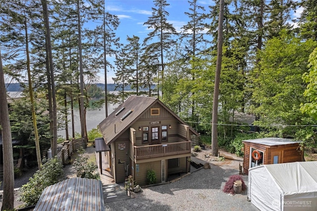 back of property featuring metal roof, view of scattered trees, and a balcony