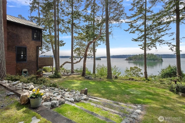 view of green lawn with a water view