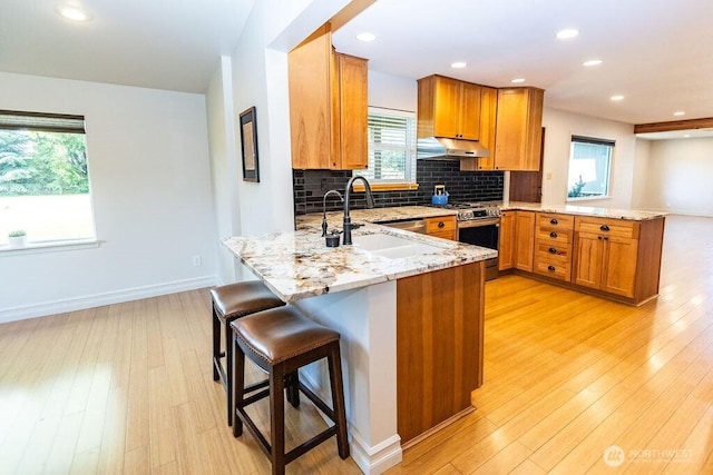 189 Hill Rd, Walla Walla, WA 99362 - kitchen with a peninsula, stainless steel range, under cabinet range hood, a sink, and light stone countertops