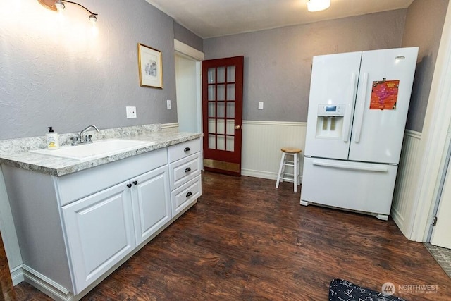 189 Hill Rd, Walla Walla, WA 99362 - kitchen featuring white fridge with ice dispenser, dark wood-style floors, white cabinets, a wainscoted wall, and a sink