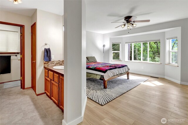 bedroom with baseboards, a sink, and light wood-style floors