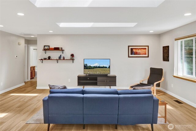 living area with a skylight, light wood-type flooring, baseboards, and recessed lighting