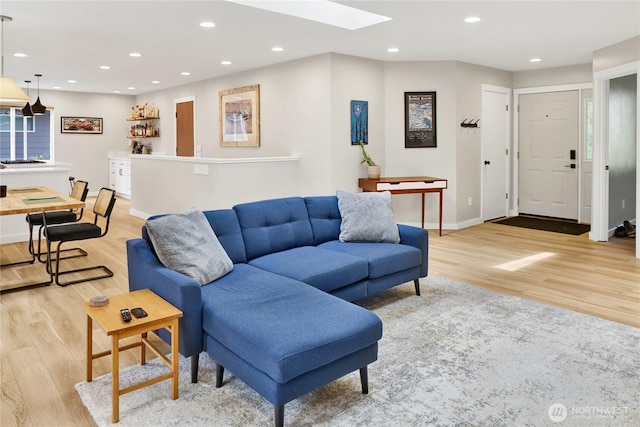 living room featuring light wood-style flooring, recessed lighting, a skylight, and baseboards