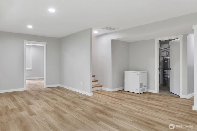 below grade area with fridge, recessed lighting, light wood-type flooring, baseboards, and stairway