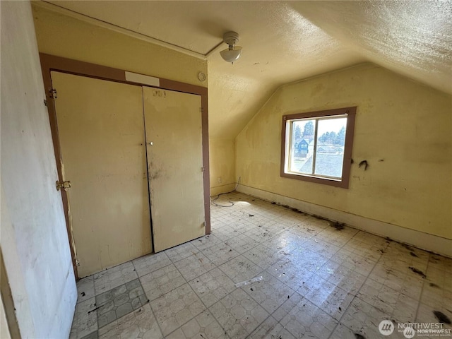 additional living space with lofted ceiling, tile patterned floors, and a textured ceiling