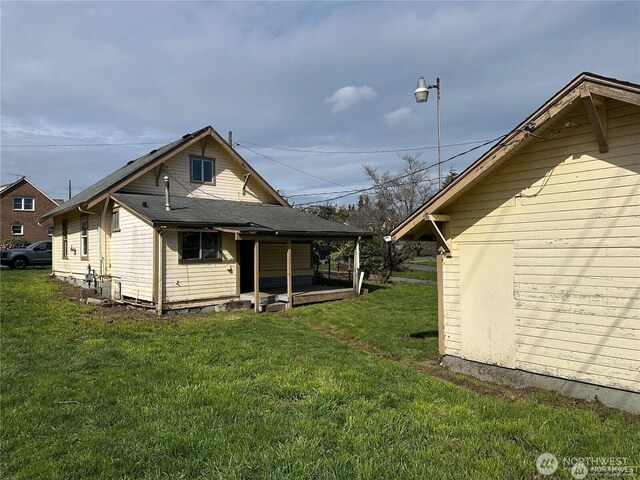 back of house featuring a lawn and covered porch