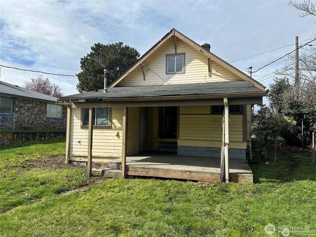 view of front of property with a front yard, a porch, a chimney, and roof with shingles