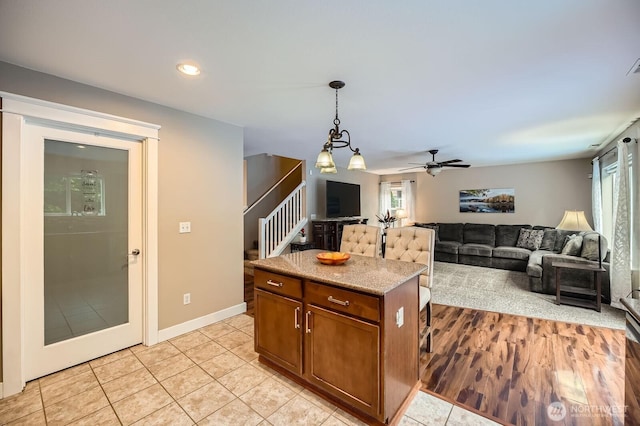 19702 99th Ct E, Bonney Lake, WA 98391 - kitchen featuring brown cabinets, hanging light fixtures, light tile patterned floors, open floor plan, and a ceiling fan