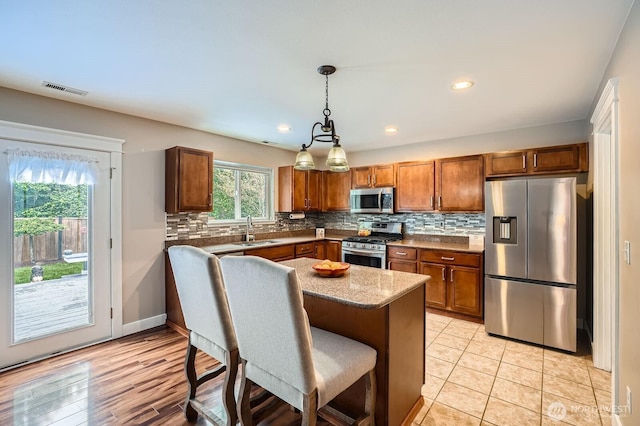 19702 99th Ct E, Bonney Lake, WA 98391 - kitchen with appliances with stainless steel finishes, a sink, brown cabinets, decorative backsplash, and a breakfast bar