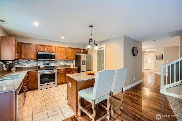 19702 99th Ct E, Bonney Lake, WA 98391 - kitchen featuring appliances with stainless steel finishes, a sink, brown cabinets, decorative backsplash, and a kitchen island