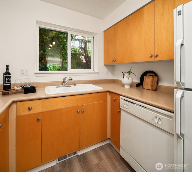 kitchen with white appliances, a sink, light countertops, and wood finished floors