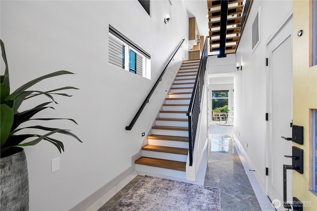 stairs featuring a high ceiling and baseboards
