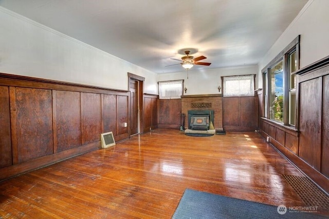 1027 E Main St, Auburn, WA 98002 - unfurnished living room featuring hardwood / wood-style floors, a ceiling fan, wainscoting, a wood stove, and wood walls