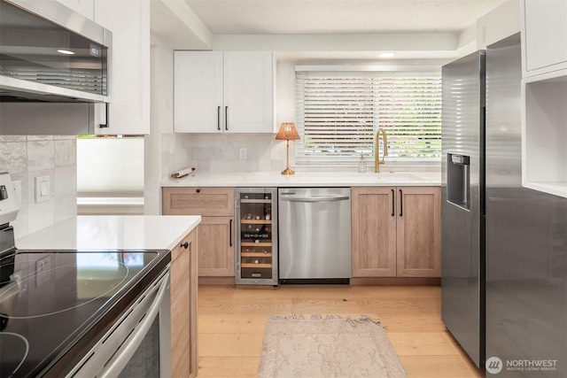 5801 Phinney Ave N Unit 103, Seattle, WA 98103 - kitchen with appliances with stainless steel finishes, wine cooler, light wood finished floors, and backsplash