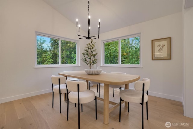 dining room with a chandelier, baseboards, light wood-style floors, healthy amount of natural light, and vaulted ceiling