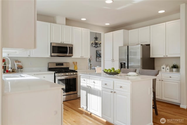 15704 124th Ave NE, Woodinville, WA 98072 - kitchen featuring appliances with stainless steel finishes, a kitchen island, light wood finished floors, white cabinetry, and recessed lighting