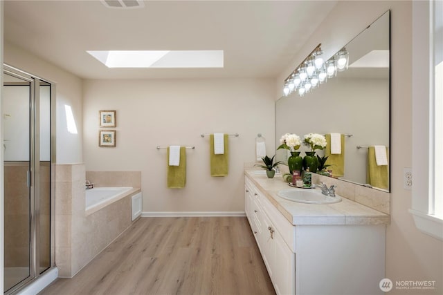 15704 124th Ave NE, Woodinville, WA 98072 - bathroom featuring a skylight, wood finished floors, a garden tub, double vanity, and a stall shower